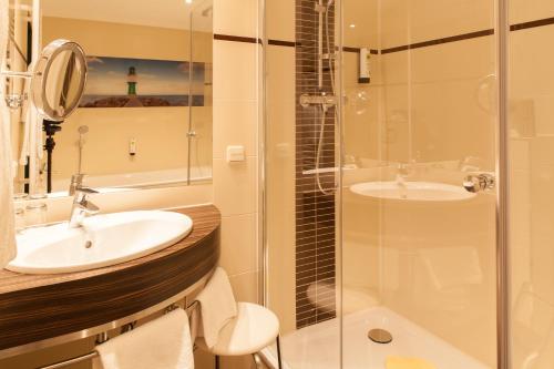 a bathroom with a sink and a shower at Trihotel Rostock - Wellnesshotel Adults Only in Rostock