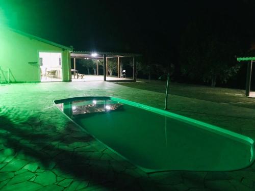 una piscina verde en medio de un patio por la noche en Chacara R. da Felicidade proximo ao thermas, aguas de sao pedro en Águas de São Pedro