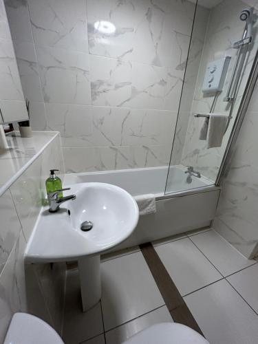 a white bathroom with a sink and a bath tub at Spacious 3 bedroom apartment close to marina, 2 parking spaces, kingsize or single beds in Southampton