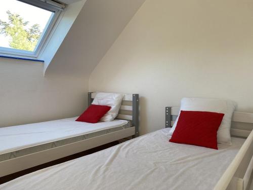 1 dormitorio con 2 camas y almohadas rojas en 606 - Appartement à Erquy, à 700m de la plage et des commerces, en Erquy