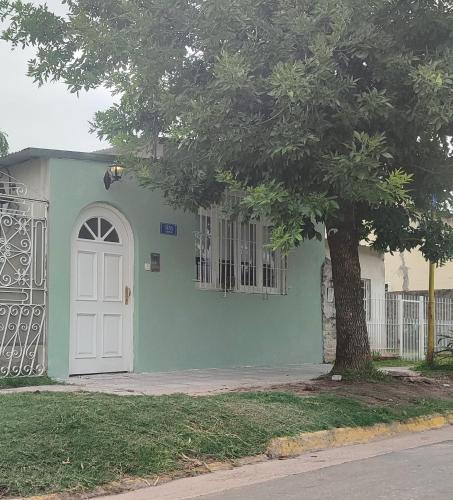 una casa verde con una puerta blanca y un árbol en La casita de Armi en Gualeguaychú