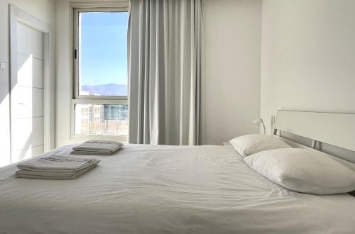 a white bed in a room with a window at Stylish 3BR Golf Residence Eilat in Eilat