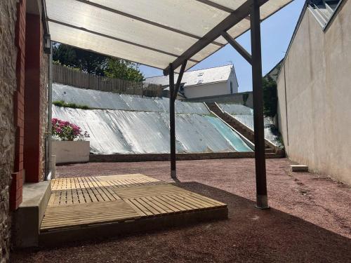 un patio avec auvent et un lit devant un bâtiment dans l'établissement 650 - Belle Maison en pierre avec jardin en plein centre d'Erquy, à Erquy