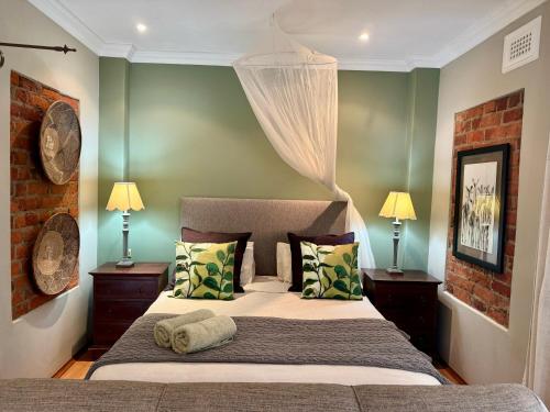 a bedroom with a large bed with two lamps and two beds sidx sidx sidx sidx at Pin Oak Cottage in Vryheid