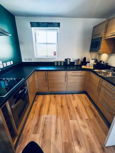 a kitchen with wooden cabinets and a wooden floor at Filey Hideaway Apartment The Bay Holiday Village Filey Homesweetholidayhomes in Filey