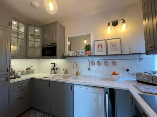 uma cozinha com balcões brancos e armários brancos em Bijou apartment in the heart of Melrose em Melrose