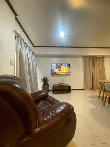 - un salon avec un canapé en cuir et une télévision à écran plat dans l'établissement The Bachelor's Suite at Mactan Airport, à Pusok