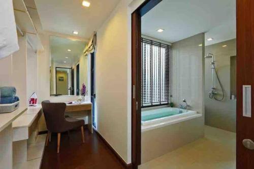 uma casa de banho com uma banheira, uma mesa e uma cadeira em Big Lucky home in Laguna park em Bang Tao Beach