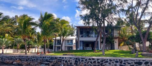 a house with palm trees in front of it at Canari Waterfront Villas in Roches Noires