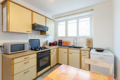 - une cuisine avec des placards en bois, un four micro-ondes et une table dans l'établissement Appartement face Mer - 50m plage, à Douarnenez