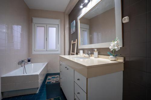 een badkamer met een wastafel, een bad en een spiegel bij Lembranzas in Padrón