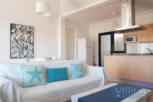 a living room with a white couch with blue pillows at VILLA BERMEJA 20 by Villitas in Playa Blanca
