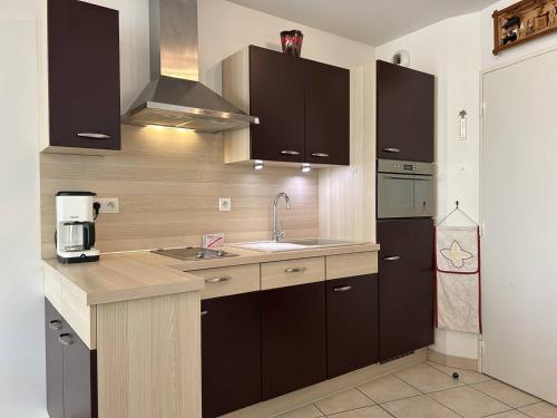 d'une cuisine avec des placards bruns et un évier. dans l'établissement 652 - Appartement avec terrasse à Erquy Centre, dans une résidence récente à 100m de la plage, à Erquy