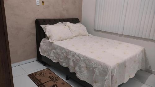 Cama pequeña en habitación con manta blanca en Casa p/ temporada, praia guaibim en Guaibim