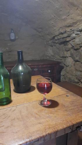 a glass of wine on a wooden table with two vases at Mátrai pincés udvar in Mátramindszent