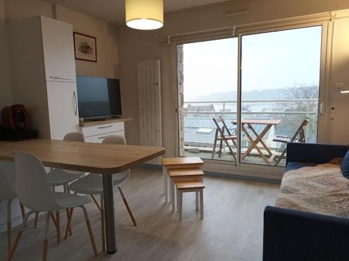ein Wohnzimmer mit Esstisch und großem Fenster in der Unterkunft 664 - Bel appartement à Erquy, à 400m de la plage du centre offrant une vue en hauteur du Port in Erquy
