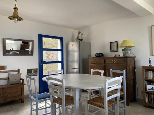 La cuisine est équipée d'une table et de chaises blanches ainsi que d'un réfrigérateur. dans l'établissement 700 - Charmante maison A ERQUY, Domaine privé de LANRUEN face à la plage, à Le Val