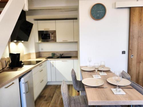 a kitchen with a table with chairs and a clock on the wall at A 150m du port, Le Baia, tout à pied in Saint-Martin-de-Ré
