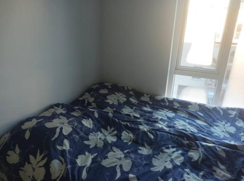 - un lit avec une couverture bleue et blanche et une fenêtre dans l'établissement Fully equipped apartment, 15 min to Center, à Copenhague