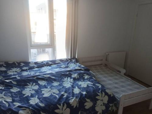 a bedroom with a bed with a blue comforter and a window at Fully equipped apartment, 15 min to Center in Copenhagen
