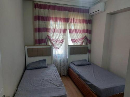 2 camas en una habitación pequeña con ventana en شقة عصرية مع تراس تطل على المدينة 6 Modern apartment with a terrace and city view, en Esenyurt