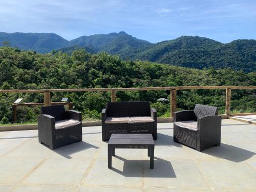 2 sillas y una mesa en un patio con montañas en Casa para temporada em meio à natureza., en Cachoeiras de Macacu