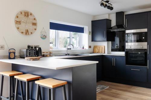 uma cozinha com armários pretos e bancadas brancas em The Beach House with Balcony North Wales em Kinmel Bay