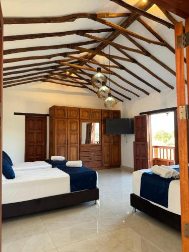 two beds in a large room with wooden ceilings at Hotel Palais Barichara in Barichara