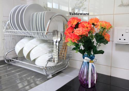 a plate rack with plates and flowers in a vase at H2H - Bintang49 Vacation House in Ipoh