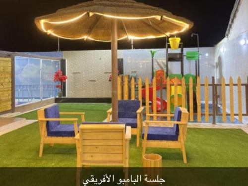 a play area with chairs and an umbrella and a playground at القصر الريفي in Al Khafji