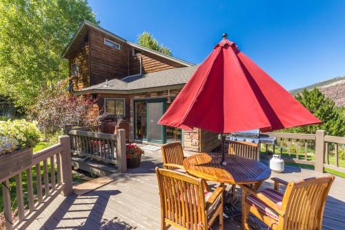 a table and chairs with a red umbrella on a deck at Mountain View in Ouray