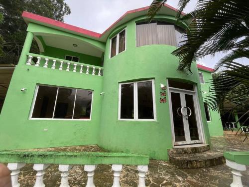 a green house with a white fence in front of it at Villa Don Manuel in Villa Altagracia