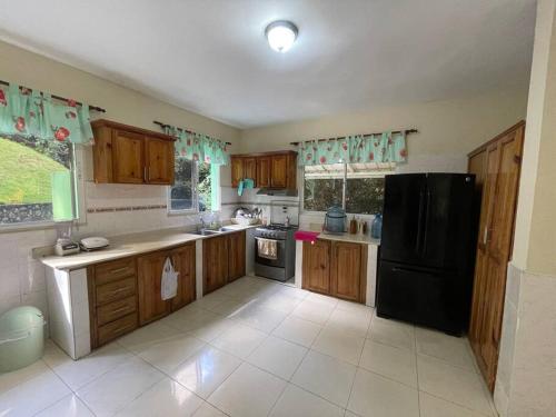 a kitchen with wooden cabinets and a black refrigerator at Villa Don Manuel in Villa Altagracia