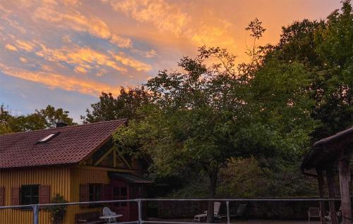 uma casa amarela com um pôr-do-sol ao fundo em 2 Bedroom Amazing Home In Wartmannsroth em Wartmannsroth