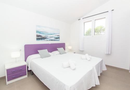 a white bedroom with two beds and a window at Villa Macarella by Sonne Villas in Cala Galdana