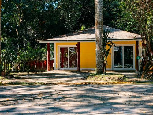 a yellow house with a tree in front of it at Hotel Cabañas River Park in Omoa