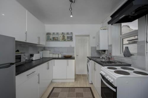a kitchen with white cabinets and a stove top oven at Beautiful Family Home in Blackpool for you in Blackpool