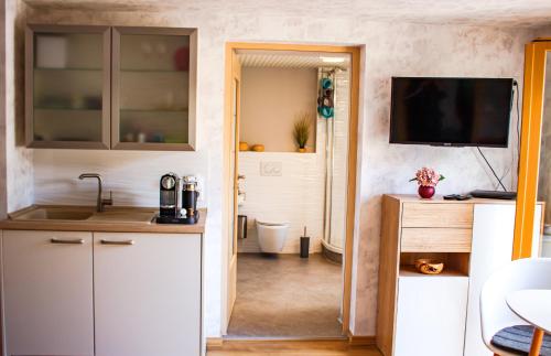 cocina con armarios blancos y TV en la pared en Harzträume No1 & No2 # Parkplatz # Altstadt # Brockenbahn, en Wernigerode