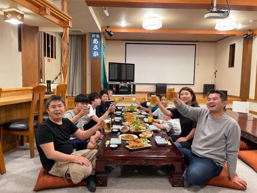 a group of people sitting around a table eating food at 源泉かけ流しの露天風呂を独り占め！一棟貸切旅館「御宿あさか」29名まで宿泊可 in Ena