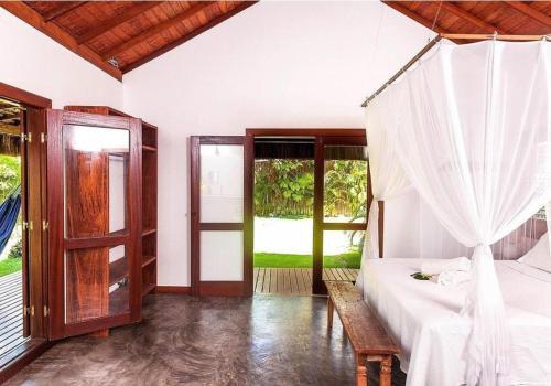 1 dormitorio con 1 cama y puerta a un patio en Casa Bora Lá en Caraíva