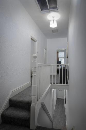 a hallway with stairs and a mirror and a light at Beautiful Family Home in Blackpool for you in Blackpool
