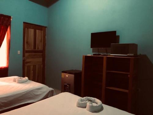 a bedroom with two beds and a tv and a dresser at Cabinas La Casona Del Pirata in La Cruz