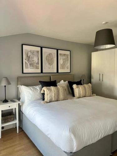 um quarto com uma grande cama branca com almofadas em Guest Homes - Rice Lane Retreat em Walton on the Hill