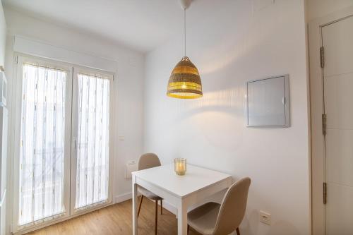 a white dining room with a white table and chairs at MQ Suites Veronica in Valdepeñas
