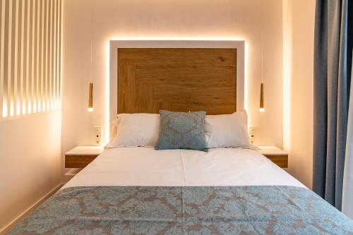 a bedroom with a large bed with a wooden headboard at MQ Suites Veronica in Valdepeñas