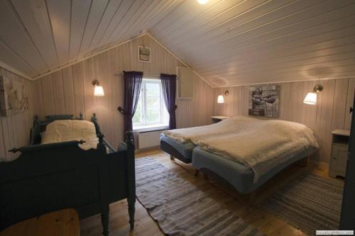 1 dormitorio en el ático con 2 camas y ventana en Edvinstua Solbakken Feriehus, en Fevåg