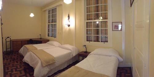1 dormitorio con 2 camas y 2 ventanas en Casa Vila Brasil - Centro Histórico, en Petrópolis