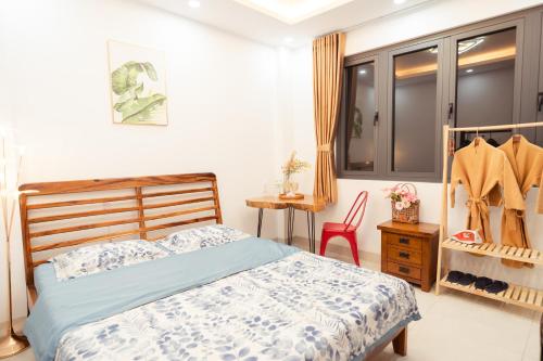 a bedroom with a bed and a table and a chair at The Sophia Apartment - Thao Dien Central in Ho Chi Minh City