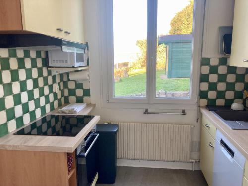 une petite cuisine avec un évier et une fenêtre dans l'établissement Les Penates, à Veules-les-Roses