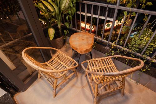 two wicker chairs and a table on a balcony at The Sophia Apartment - Thao Dien Central in Ho Chi Minh City